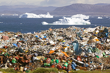 Rubbish dumped on the tundra outside Ilulissat in Greenland with icebergs behind from the Sermeq Kujullaq (Ilulissat Ice fjord), a UNESCO World Heritage Site, Greenland, Polar Regions