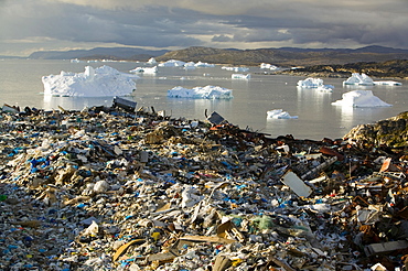 Rubbish dumped on the tundra outside Ilulissat in Greenland with icebergs behind from the Sermeq Kujalleq (Ilulissat Ice fjord), a UNESCO World Heritage Site, Greenland, Polar Regions