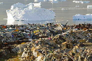 Rubbish dumped on the tundra outside Ilulissat in Greenland with icebergs behind from the Sermeq Kujalleq (Ilulissat Ice fjord), a UNESCO World Heritage Site, Greenland, Polar Regions