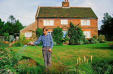 A man watering his garden in Aylsham. Norfolk, England, United Kingdom, Europe