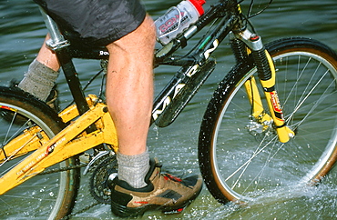 A mountain biker riding through Rydal Water in the Lake District, Cumbria, England, United Kingdom, Europe