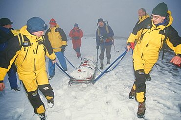 Mountain Rescue team members drag a sled across the mountain tops with the body of a dead heart attack victim, Lake District, Cumbria, England, United Kingdom, Europe