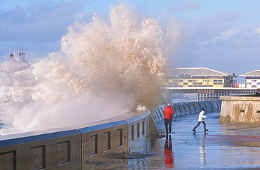 People dodging storm waves breaking over the sea wall at Blackpool, Lancashire, England, United Kingdom, Europe