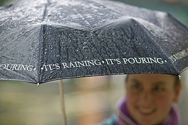 A woman using an umbrella in the rain in Ambleside, Cumbria, England, United Kingdom, Europe