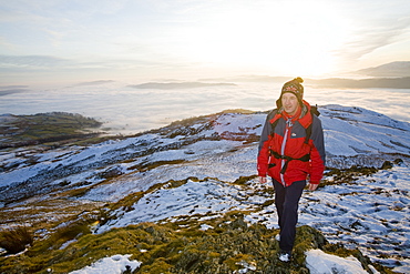 A walker on Wansfell Pike with valley mist below, Lake District National Park, Cumbria, England, United Kingdom, Europe