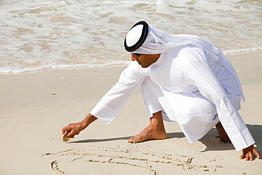 An Arab man wearing traditional dress on a beach in Dubai, United Arab Emirates, Middle East