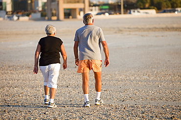 An overweight elderly couple taking exercise on a public beach in Dubai, United Arab Emirates, Middle East