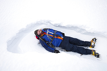 A man lying in the snow on Crinkle Crags in the Lake District, Cumbria, England, United Kingdom, Europe