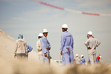 Workers working on reclaiming land from the sea for another exclusive hotel development in Dubai, United Arab Emirates, Middle East