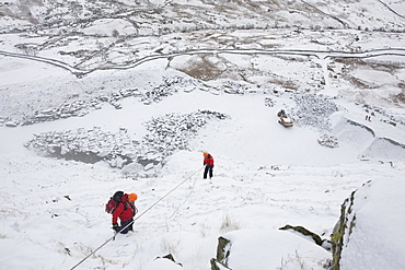 A mountain rescue team member abseiling in the snow above Kirkstone near Ambleside in the Lake District, Cumbria, England, United Kingdom, Europe