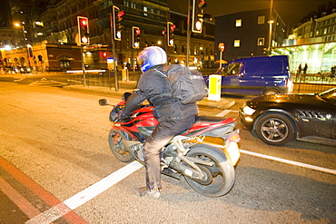 A motorcyclist at night outside Kings Cross, London, England, United Kingdom, Europe