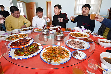 Chinese people sit down for a meal in a restaurant which includes several dishes of dog meat, China, Asia