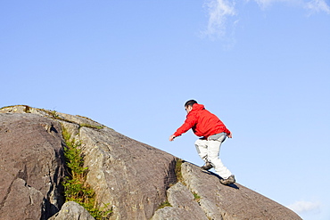 A man running up a boulder above Chapel Stile in the Langdale Valley in the Lake District, Cumbria, England, United Kingdom, Europe