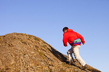 A man running up a boulder above Chapel Stile in the Langdale Valley in the Lake District, Cumbria, England, United Kingdom, Europe