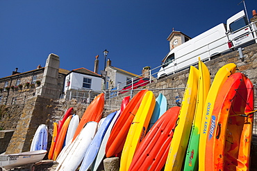 Canoes leaned up against the sea wall in Mousehole in Cornwall, England, United Kingdom, Europe