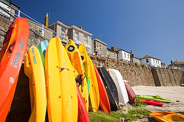 Canoes leaned up against the sea wall in Mousehole in Cornwall, England, United Kingdom, Europe