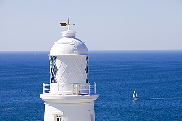 A sailing boat sails past Pendeen Watch lighthouse near St. Just in Cornwall, England, United Kingdom, Europe