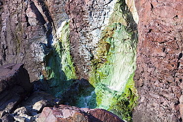 Sea cliffs stained green from copper deposits leaching from the old Geevor Tin Mine near St. Just in Cornwall, England, United Kingdom, Europe