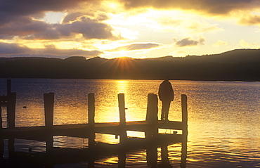 A man on a jetty on Coniston Water in the Lake District at sunset, Cumbria, England, United Kingdom, Europe