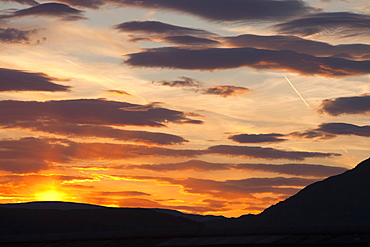 A plane flying through sunset clouds over Ambleside, Cumbria, England, United Kingdom, Europe