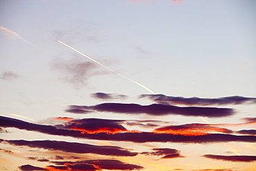 A plane flying through sunset clouds over Ambleside, Cumbria, England, United Kingdom, Europe