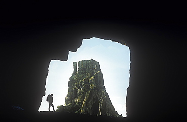 A walker in the Carsaig Arches, sea arches on the coast of Mull, Scotland, United Kingdom, Europe