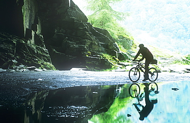 A man mountain biking in Rydal Cave, Lake District, Cumbria, England, United Kingdom, Europe