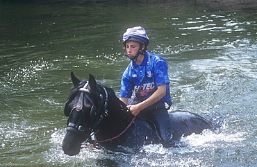 A gipsy man rides his horse through the River Eden at Appleby during the Appleby Horse Fair, Cumbria, England United Kingdom, Europe