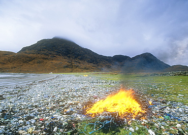 Burning plastic rubbish washed up on a beach on the Isle of Skye near Elgol, Scotland, United Kingdom, Europe