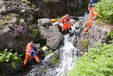 Paramedics from the Great North Air Ambulance and members of Langdale/Ambleside Mountain Rescue Team treat an injured man who fell into Wrynose Beck, before transferring him to hospital via helicopter. Lake District, Cumbria, England, United Kingdom, Europe