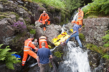 Paramedics from the Great North Air Ambulance and members of Langdale/Ambleside Mountain Rescue Team treat an injured man who fell into Wrynose Beck, before transferring him to hospital via helicopter. Lake District, Cumbria, England, United Kingdom, Europe