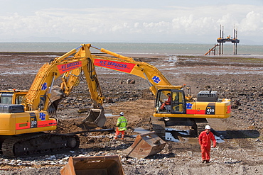 Construction workers working on the foreshore of the Solway Firth near Workington, Cumbria, England, United Kingdom, Europe