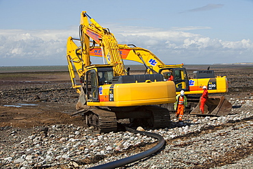 Construction workers installing a power cable on the foreshore of the Solway Firth near Workington, Cumbria, England, United Kingdom, Europe