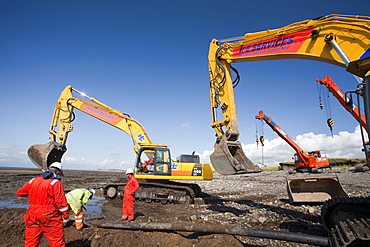 Construction workers installing a power cable on the foreshore of the Solway Firth near Workington, Cumbria, England, United Kingdom, Europe