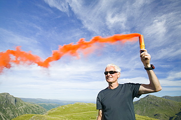 Member of the Langdale Ambleside mountain rescue team attracts a helicopter to an injured walker on Bow Fell in the Lake District, Cumbria, England, United Kingdom, Europe