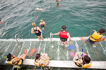 Tourists snorkelling from a dive and snorkel platform anchored to the Great Barrier Reef off Cairns in Queensland, Australia, Pacific