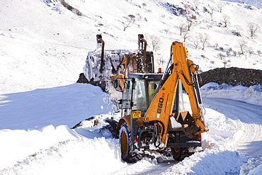 Charlie Middleton, an employee of Cumbria County Council clears snow from the blocked Kirkstone Pass, the highest mountain pass in the Lake District, Cumbria, England, United Kingdom, Europe