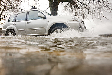 Car driving through floodwater in Ambleside when Lake Windermere broke its banks and spilled over onto the road, Lake District, Cumbria, England, United Kingdom, Europe