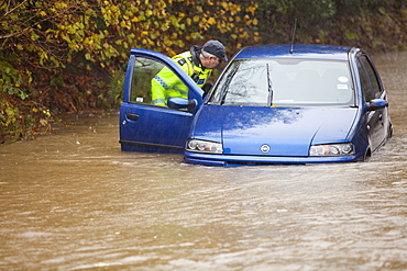 PC Paul Burke examining an abandoned flooded out car near Ambleside, Cumbria, England, United Kingdom, Europe