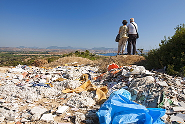 A couple look over the countryside near Teos, with illegally dumped rubbish in the foreground, Turkey, Eurasia