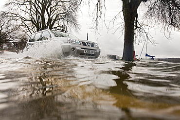 Car driving through floodwater in Ambleside when Lake Windermere broke its banks and spilled over onto the road, Lake District, Cumbria, England, United Kingdom, Europe