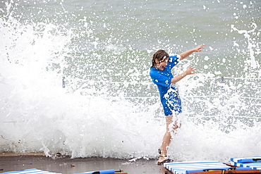 Child dodging storm waves at a holiday resort in Teos, Western Turkey, Eurasia