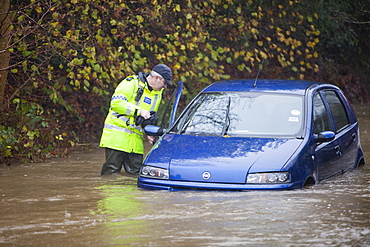 PC Paul Burke examining an abandoned flooded out car near Ambleside, Cumbria, England, United Kingdom, Europe