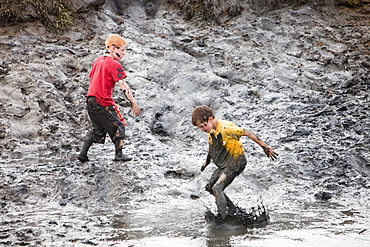 Children playing in a muddy creek at Blakeney, North Norfolk, England, United Kingdom, Europe