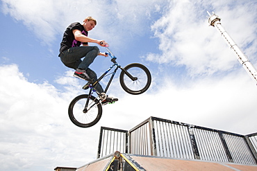 Teenage boys perform aerial stunts on BMX bikes at a BMX park in Rhyl, North Wales, United Kingdom, Europe