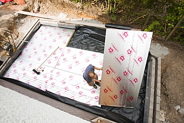 Builders lay under floor insulation into a house extension in Ambleside, Cumbria, England, United Kingdom, Europe