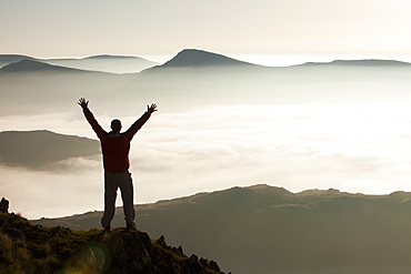 A mountaineer looking towards the Kentmere Fells, above a temperature inversion with valley mist from Red Screes near Ambleside, Lake District National Park, Cumbria, England, United Kingdom, Europe