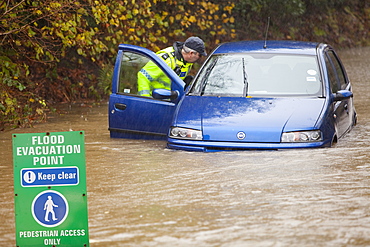 PC Paul Burke examining an abandoned flooded out car near Ambleside, Cumbria, England, United Kingdom, Europe