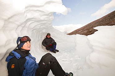 Mountaineers sheltering in an old snow hole in snow banked against an esker in Coire an Sneachda in the Cairngorms, Scotland, United Kingdom, Europe