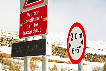 A road sign at Kirkstone Pass summit in winter snow, Lake District, Cumbria, England, United Kingdom, Europe